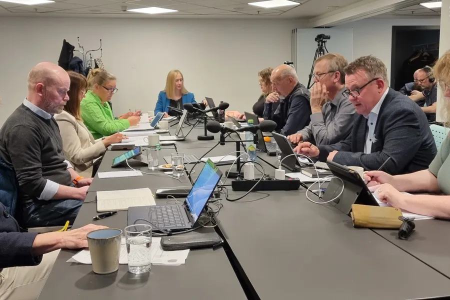 En gruppe mennesker som sitter rundt et bord med bærbare datamaskiner