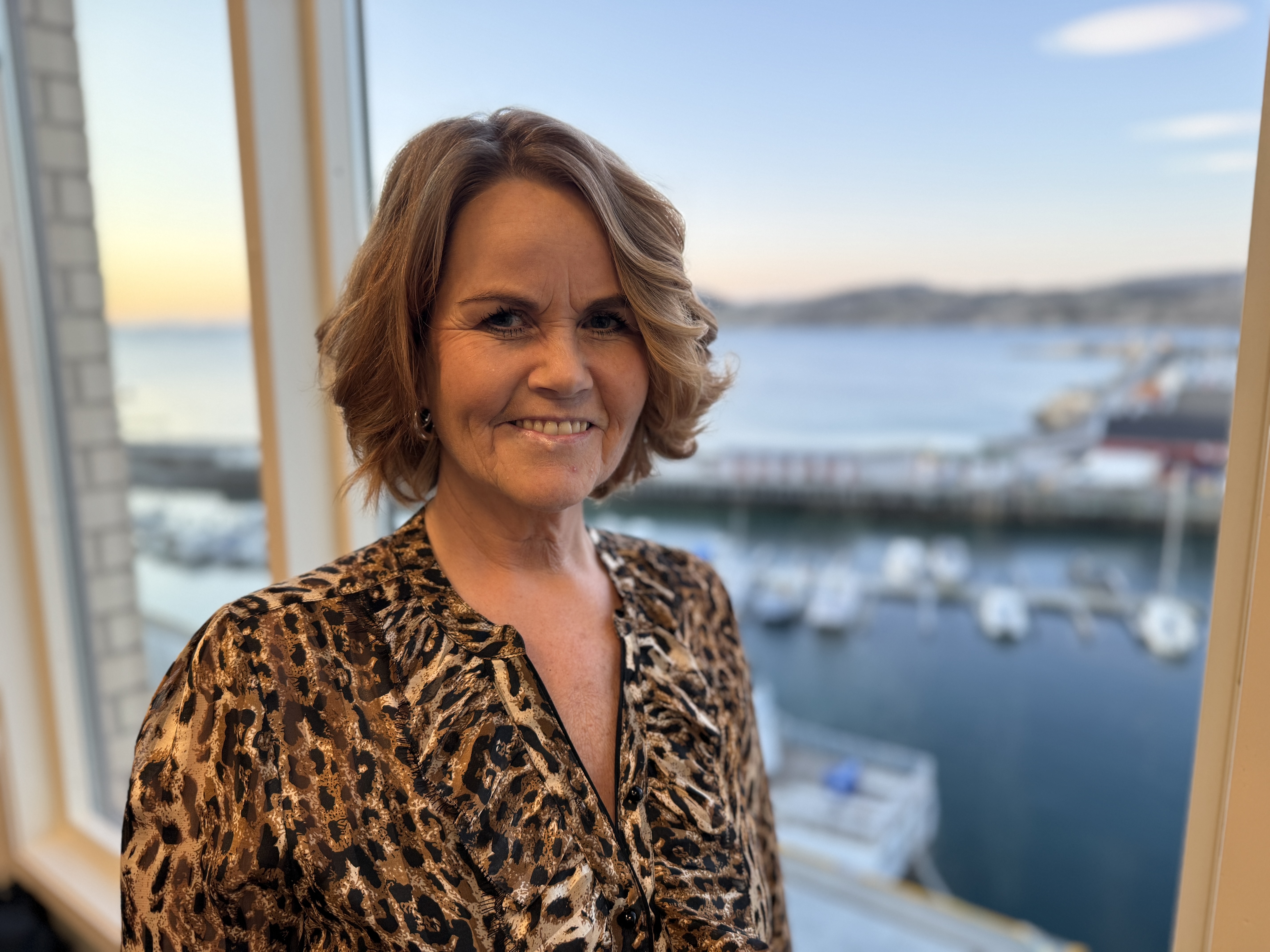 En kvinne som smiler foran et vindu