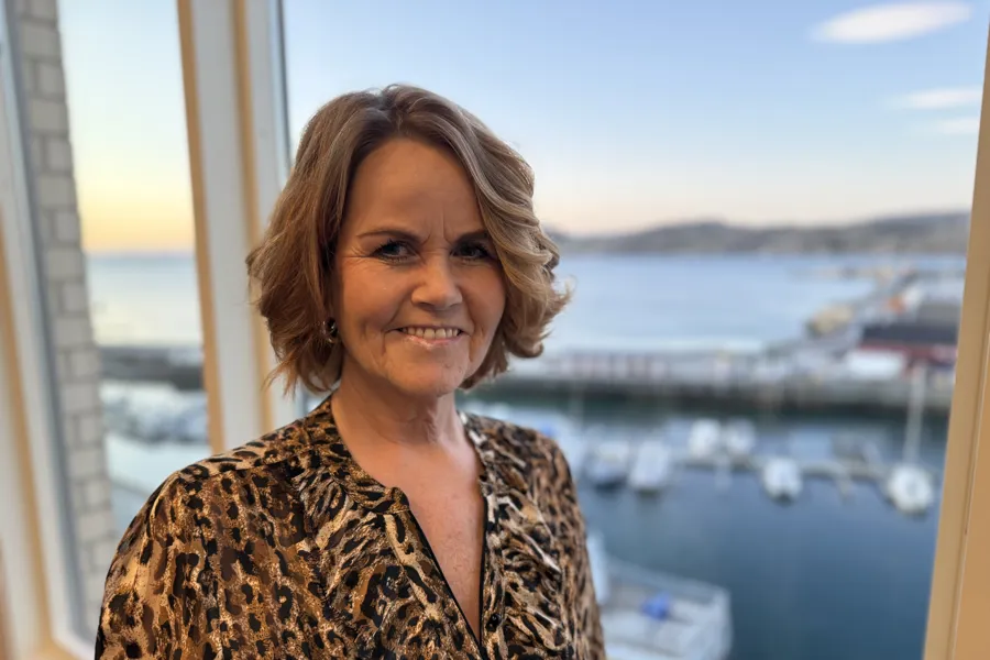 En kvinne som smiler foran et vindu