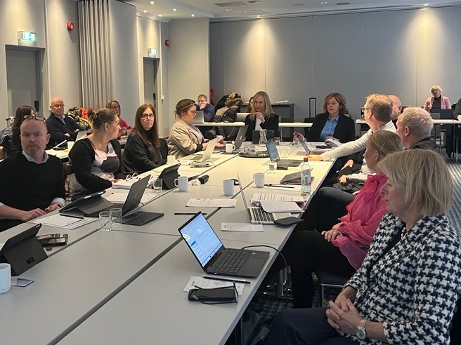 En gruppe mennesker som sitter rundt et bord med bærbare datamaskiner