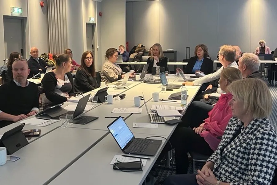 En gruppe mennesker som sitter rundt et bord med bærbare datamaskiner