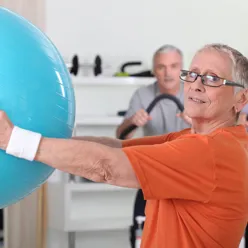 En kvinne som holder en blå ball i et treningsstudio