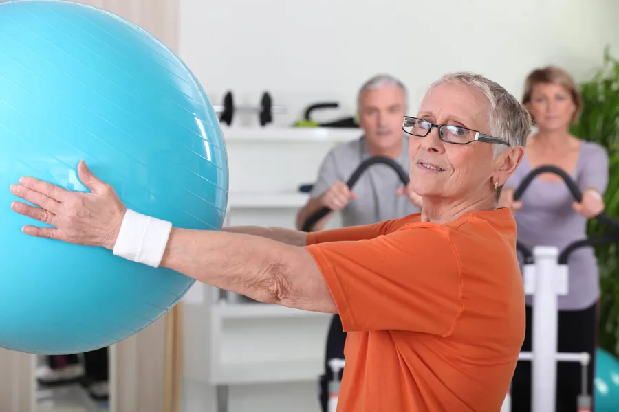 En kvinne som holder en blå ball i et treningsstudio