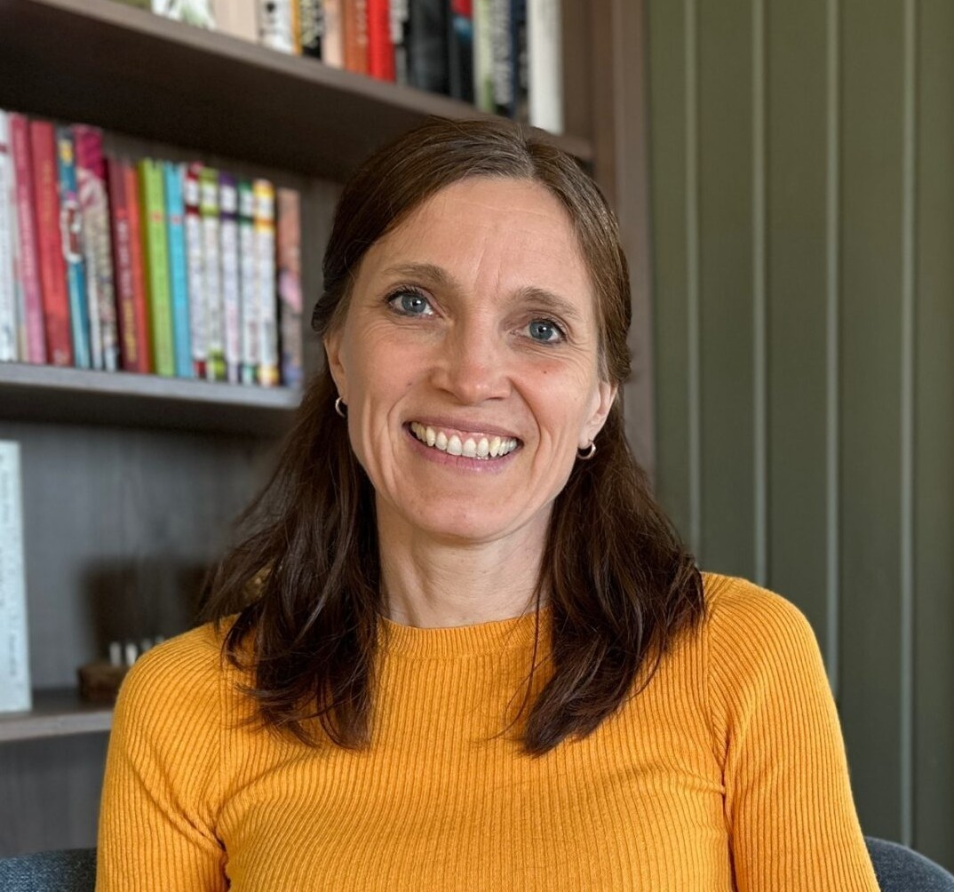 A woman smiling in front of a bookshelf