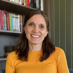 A woman smiling in front of a bookshelf