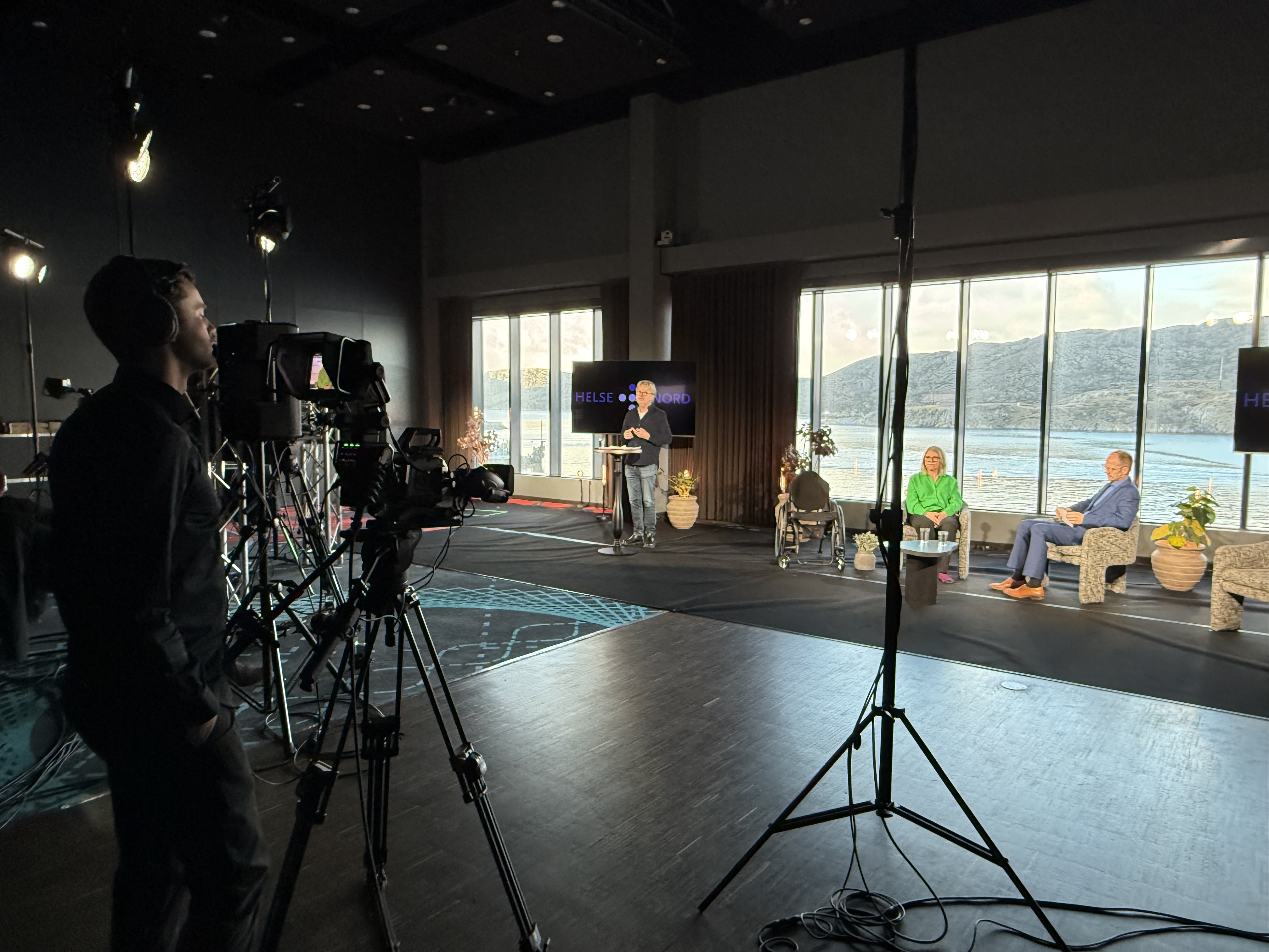 Tre personer på en scene med et kamera foran seg