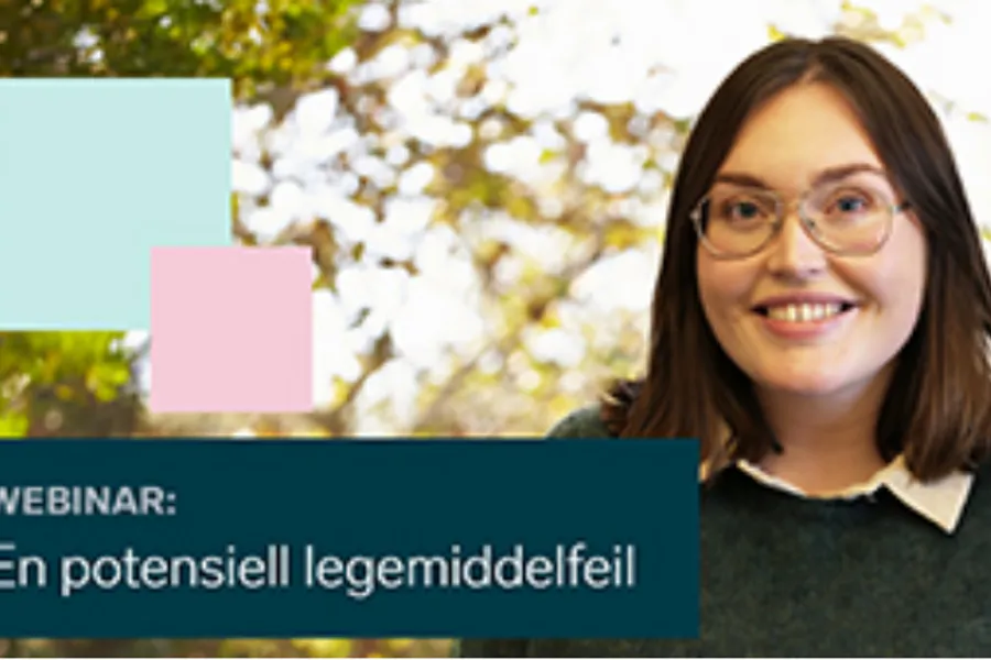 En kvinne som smiler med et skilt bak seg