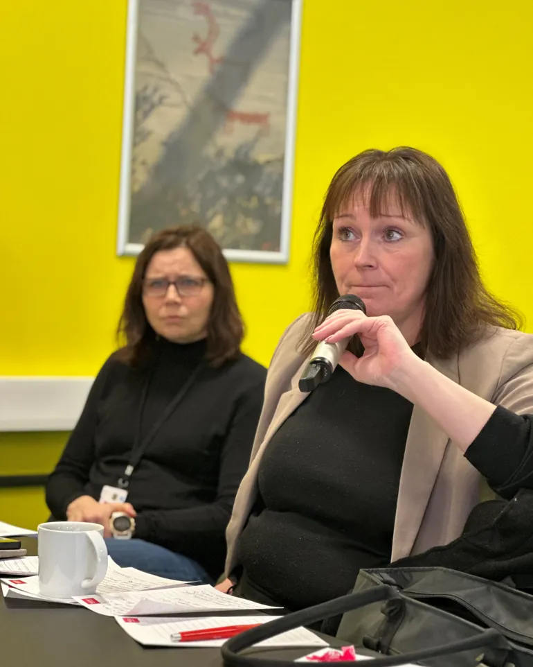 Et par kvinner som sitter ved et bord med mikrofoner