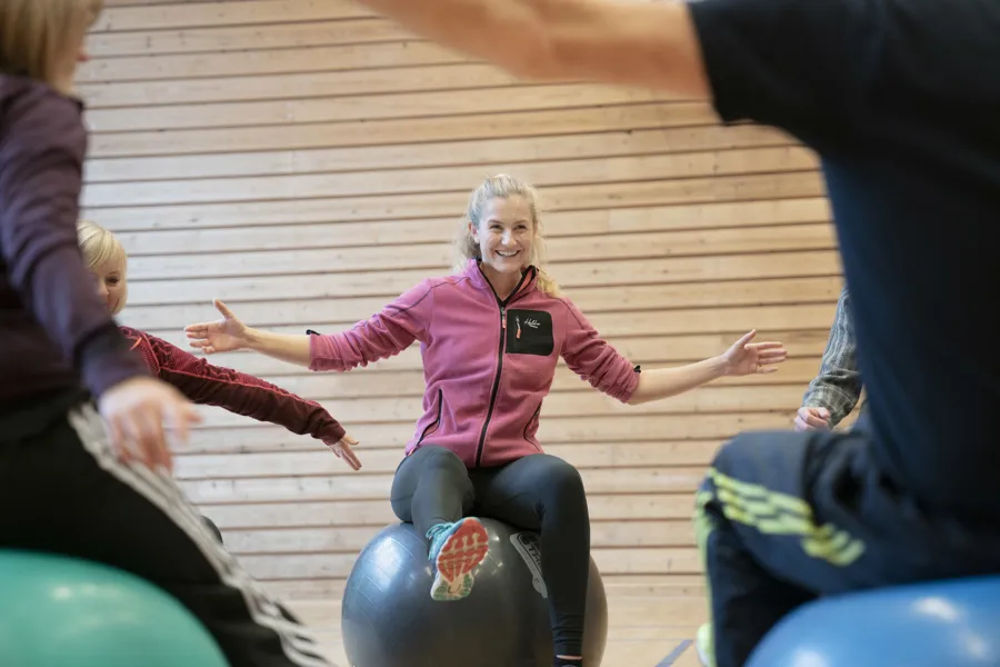 Mennesker i en gymsal på gymballer.