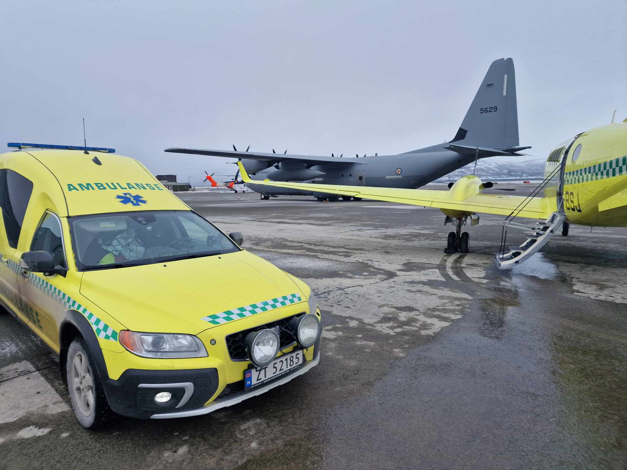 En gul bil parkert ved siden av et helikopter