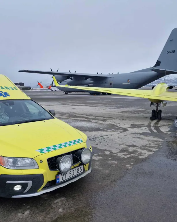 En gul bil parkert ved siden av et helikopter