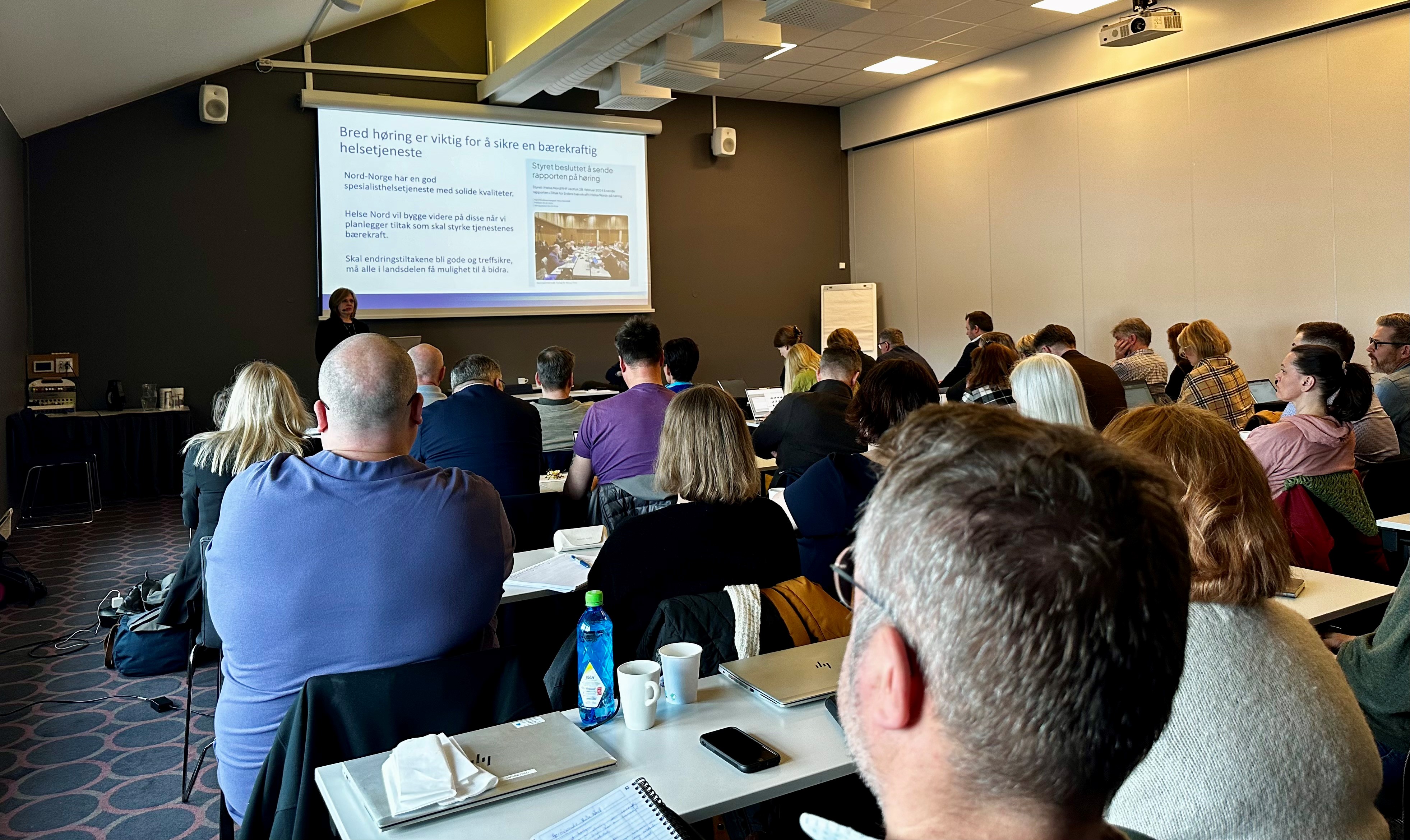 En gruppe mennesker som sitter i et rom og ser på en skjerm