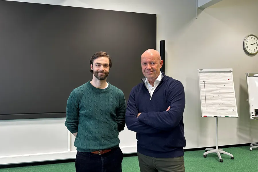 Et par menn som står foran en tavle