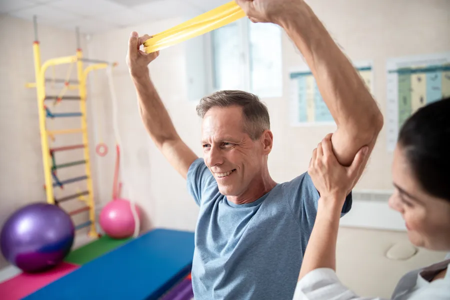 Mann som trener for rehabilitering med fysioterapeut