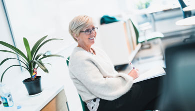 Eva Stensland, sittende, smiler, noterer