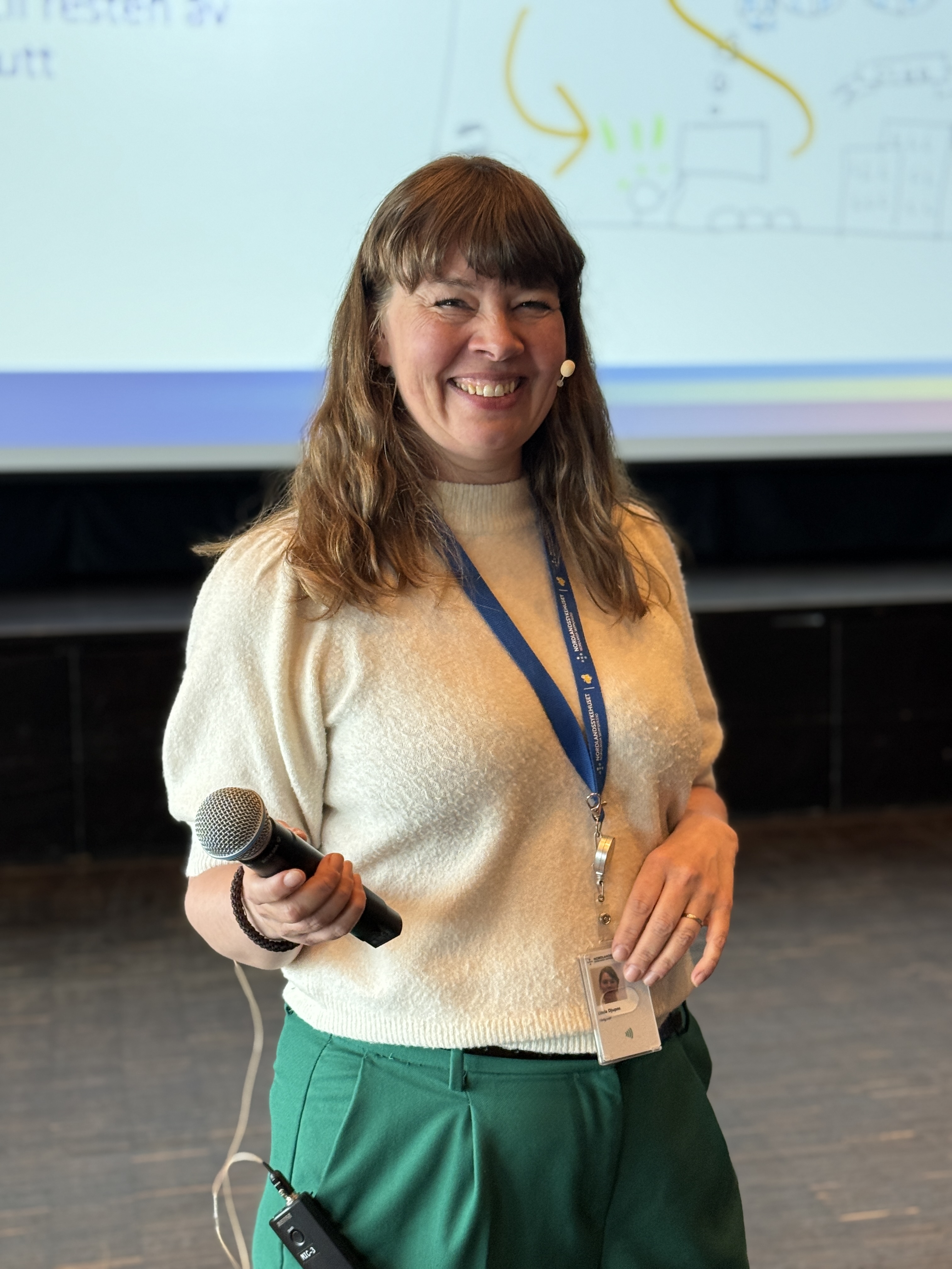 En person som smiler og holder en telefon