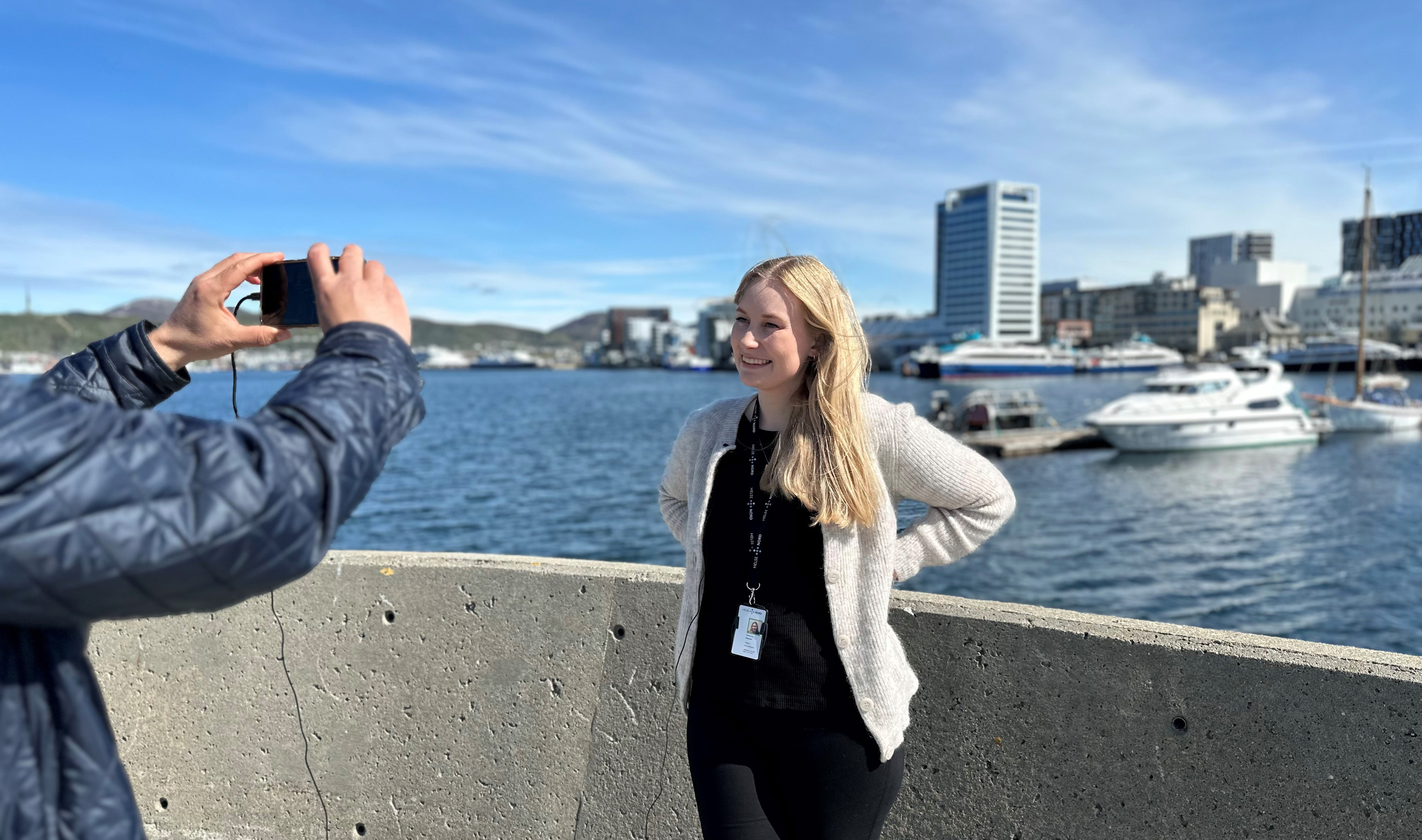 En person som tar et bilde av en person foran en vannmasse