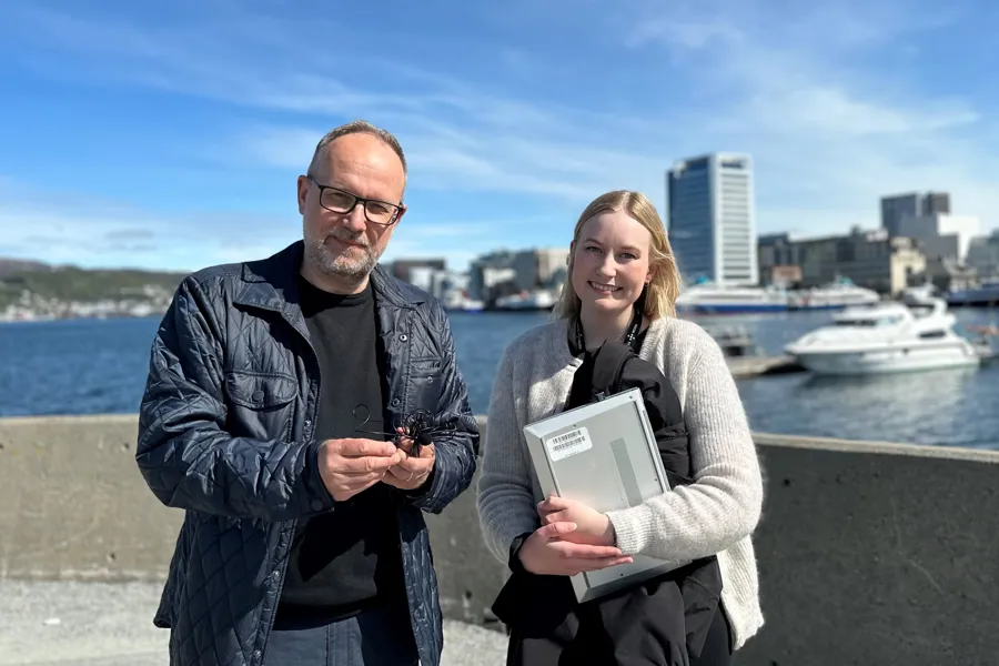 En mann og kvinne som poserer for et bilde med en vannmasse bak seg