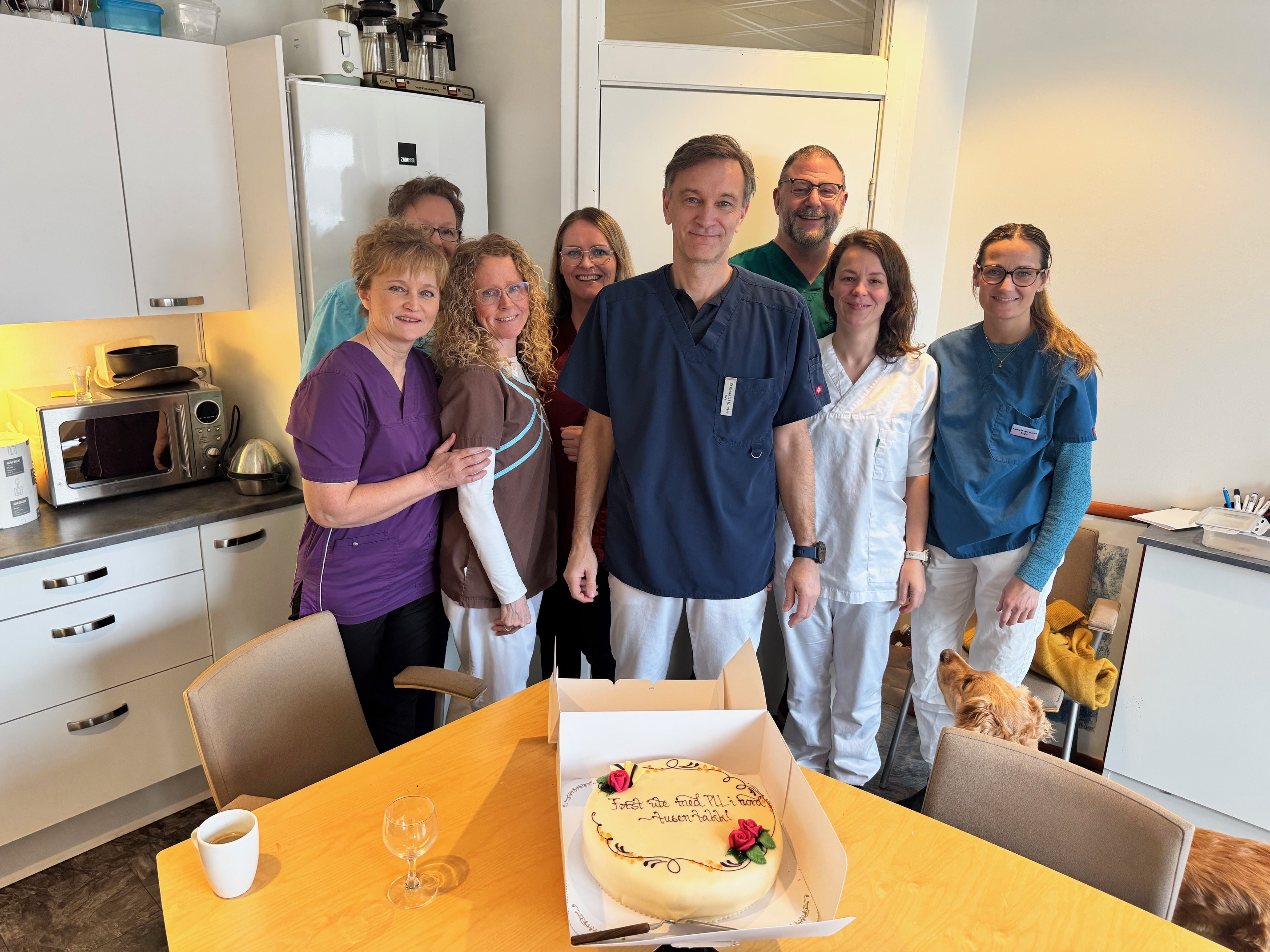 En gruppe mennesker som står rundt en kake