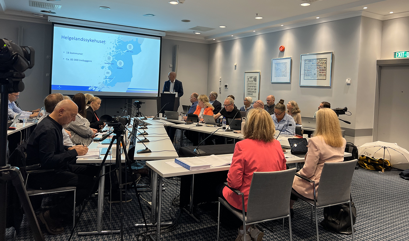 En gruppe mennesker som sitter ved et bord med en projektorskjerm