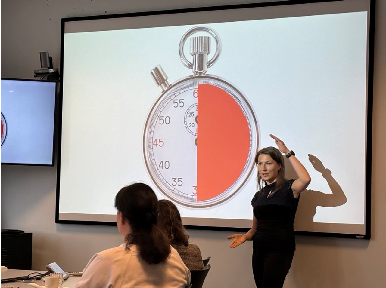 En person som står foran en tavle med en klokke på