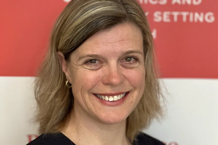 En person som smiler foran et rødt skilt