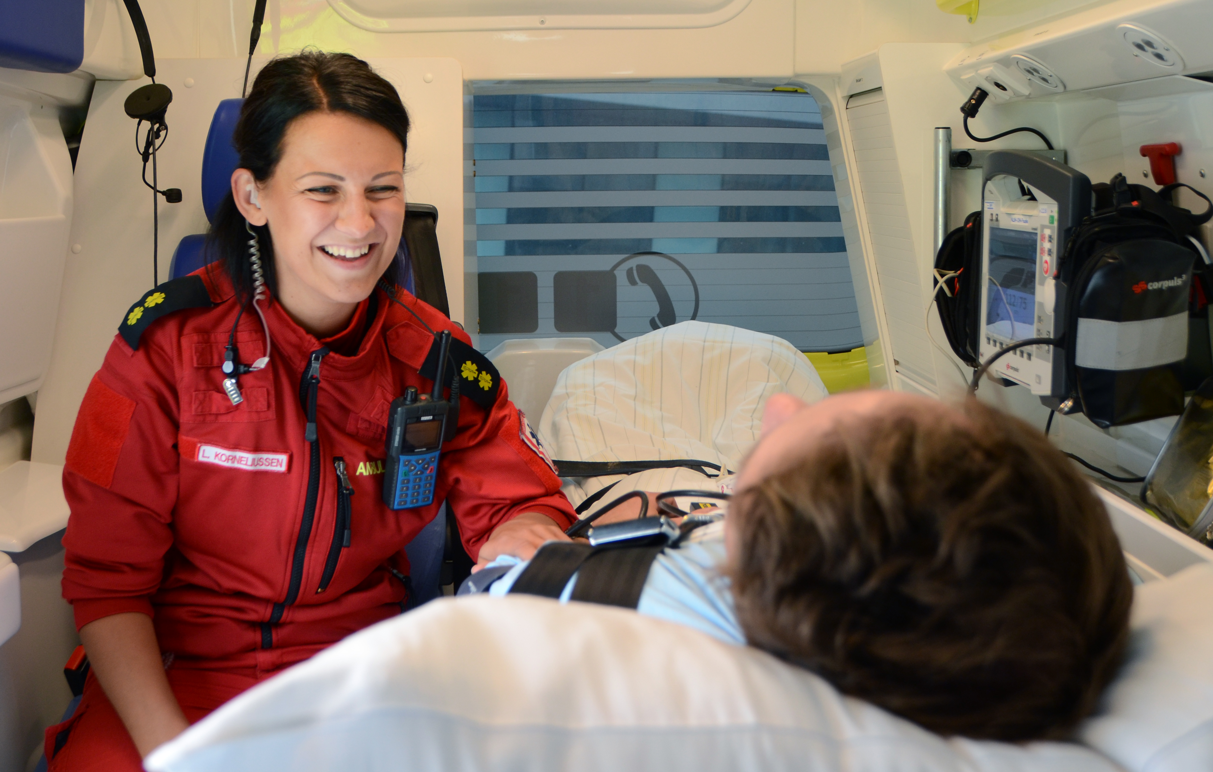 Smilene ambulansearbeider inne i ambulanse sammen med pasient