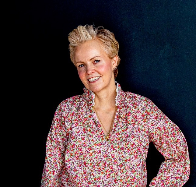 En kvinne som smiler med hendene i lommene