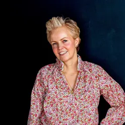 En kvinne som smiler med hendene i lommene