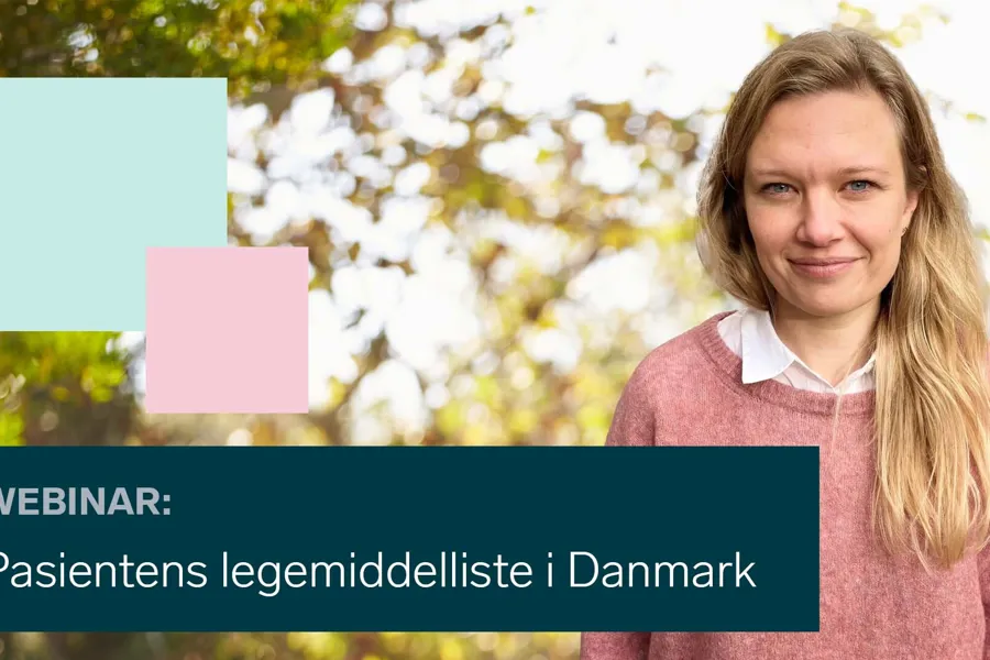 En person som smiler med et skilt bak