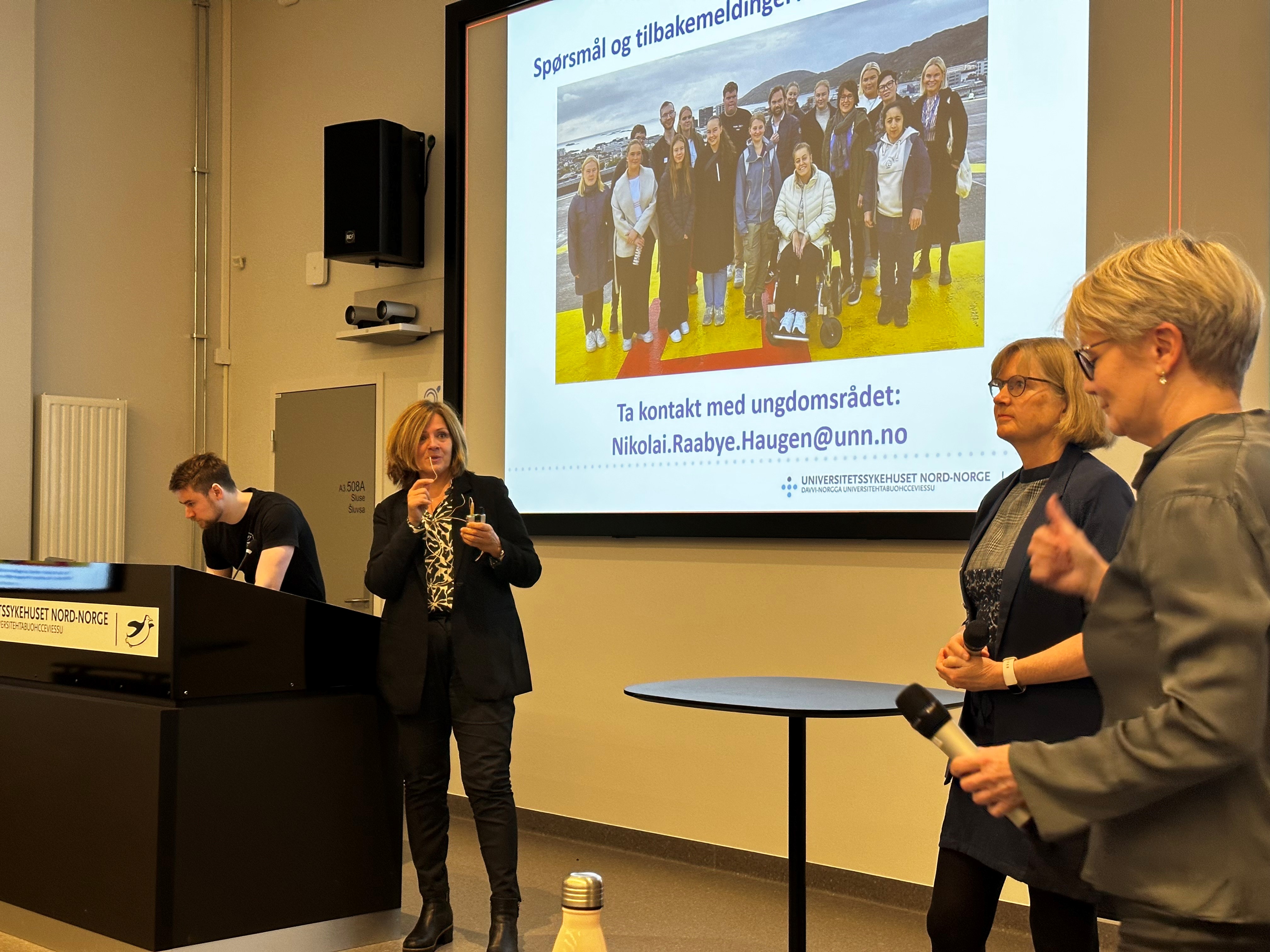 En gruppe mennesker som står foran en projektorskjerm