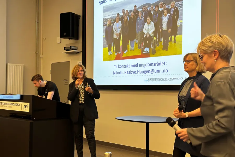 En gruppe mennesker som står foran en projektorskjerm