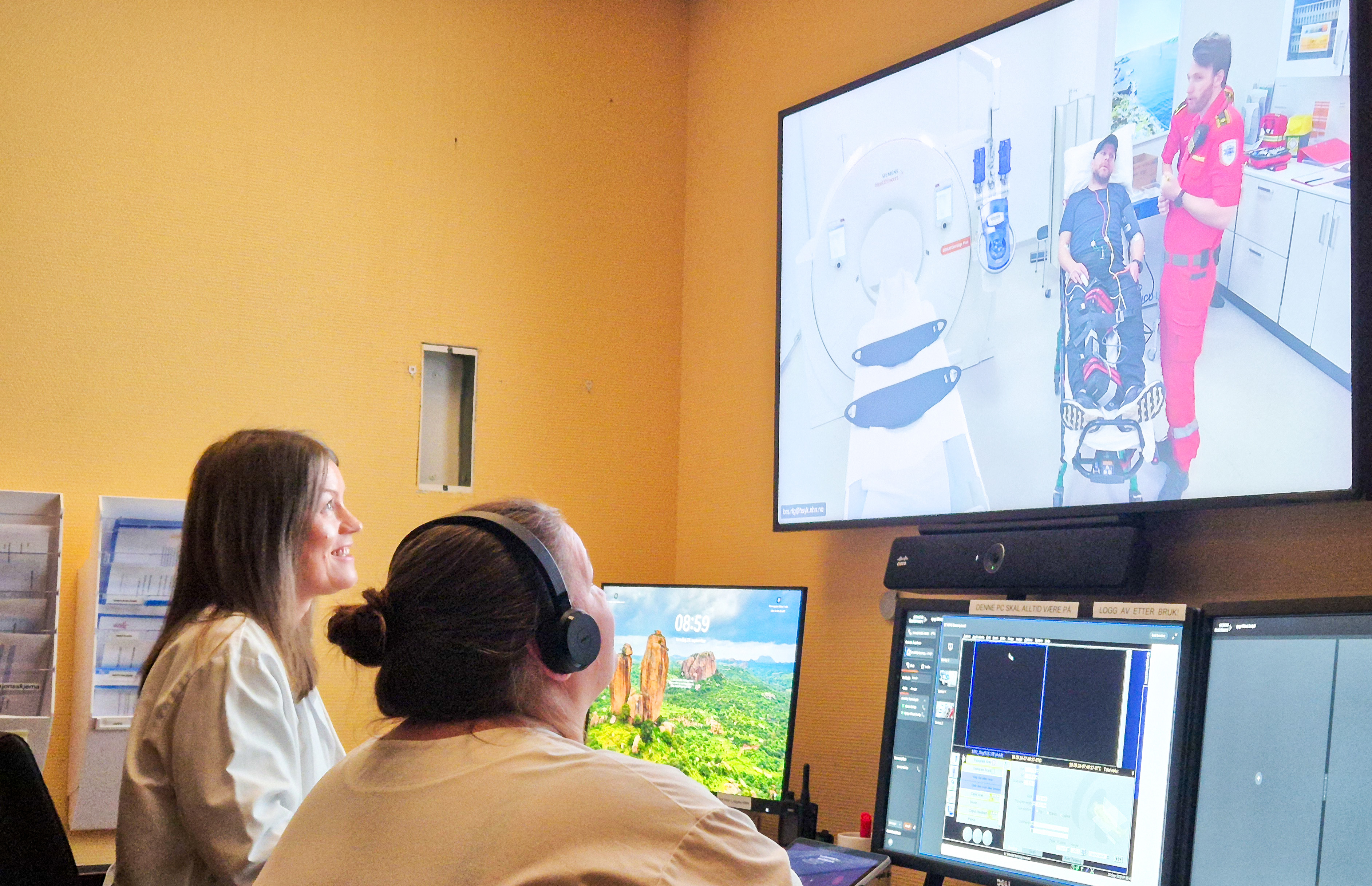 En kvinnelig lege og radiograf ser på en skjerm som viser pasient og ambulansearbeider