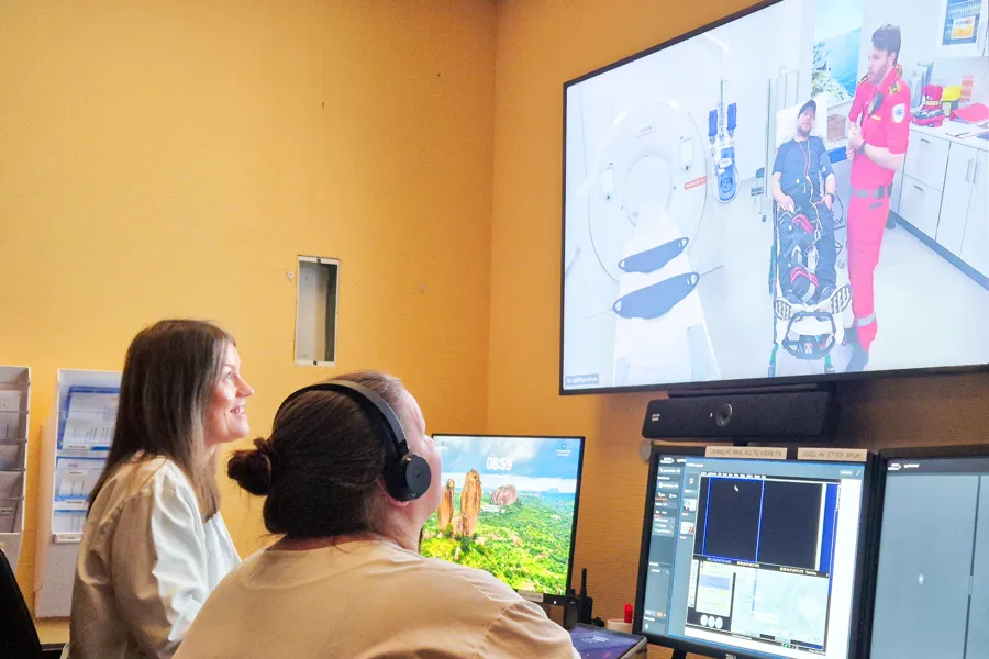 En kvinnelig lege og radiograf ser på en skjerm som viser pasient og ambulansearbeider