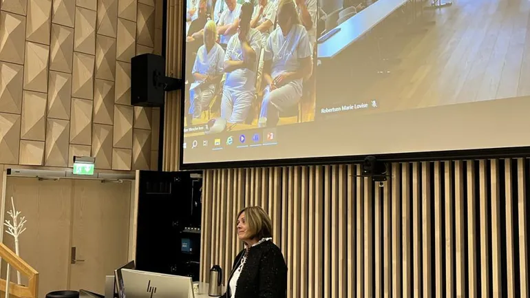 En person som står foran en stor skjerm