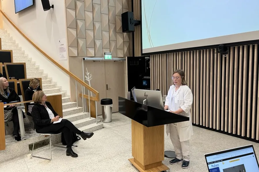 En person som står foran et podium med en person som sitter ved den