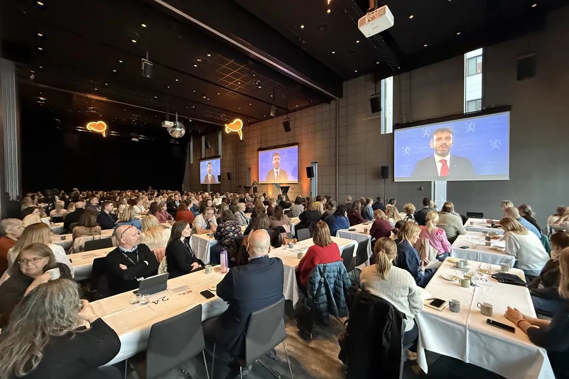 En gruppe mennesker som sitter ved bord og ser på en presentasjon
