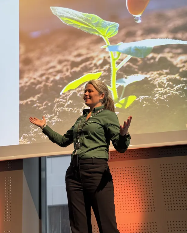 En person med lue og mikrofon med en stor fargerik fugl som flyr i luften
