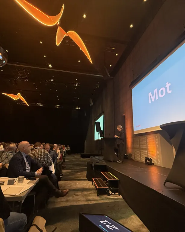 En gruppe mennesker som sitter i et rom med en stor skjerm