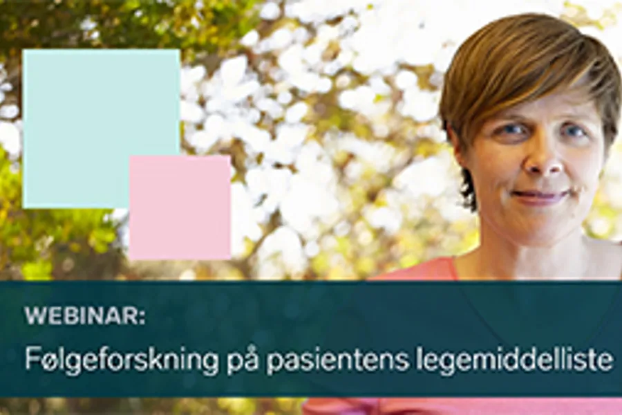 En person som smiler med et skilt bak