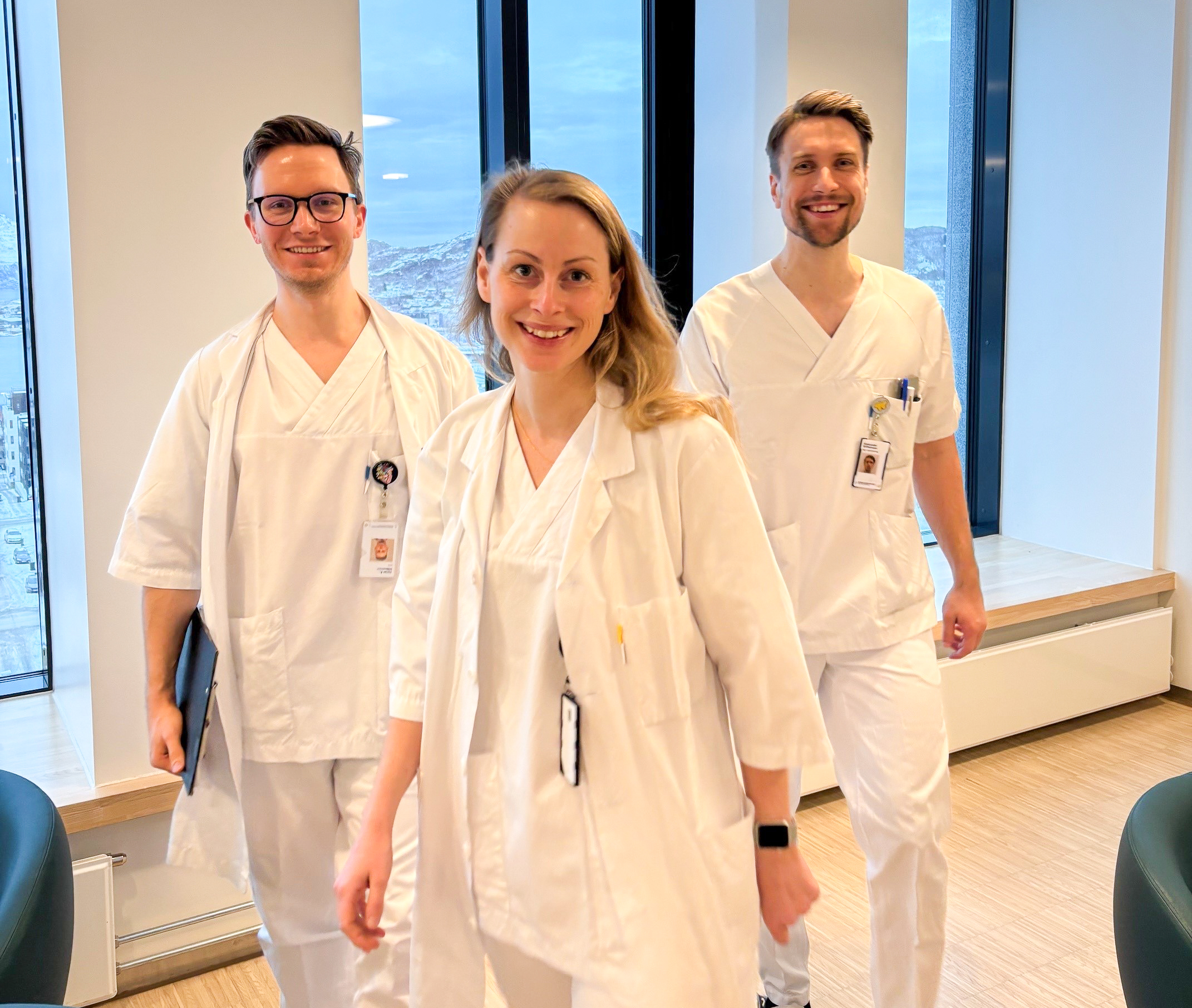 En gruppe mennesker iført hvite laboratoriefrakker og står foran et vindu