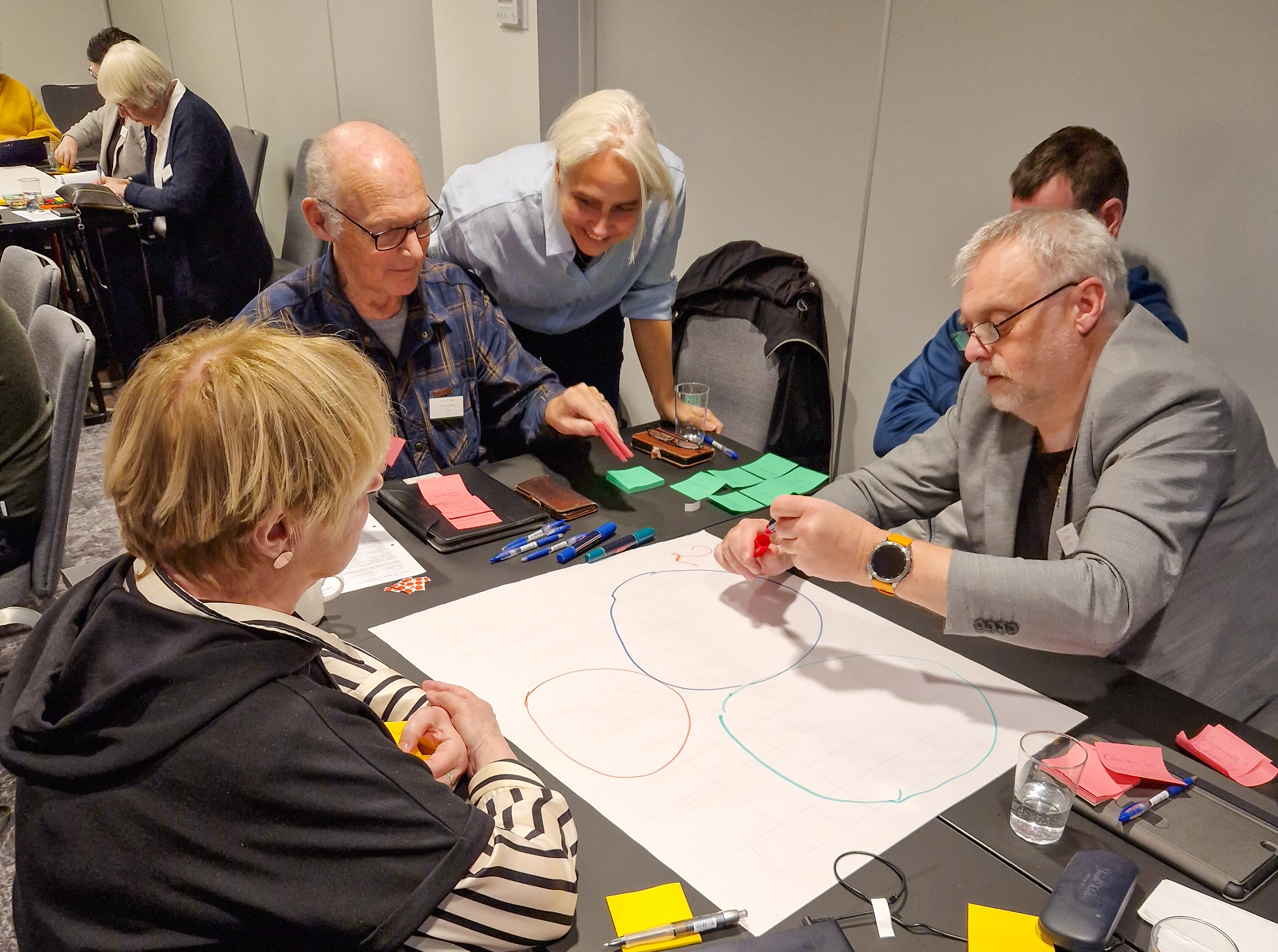 Mennesker rundt et bord som samarbeider