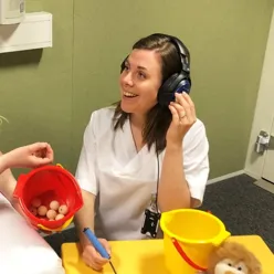 En person som har på seg hodetelefoner og holder en enhet mot øret