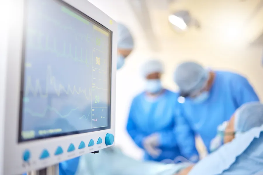Leger jobber med pasient i operasjonssal med monitor i forgrunnen