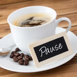 En kopp kaffe og bønner, skilt det står Pause på