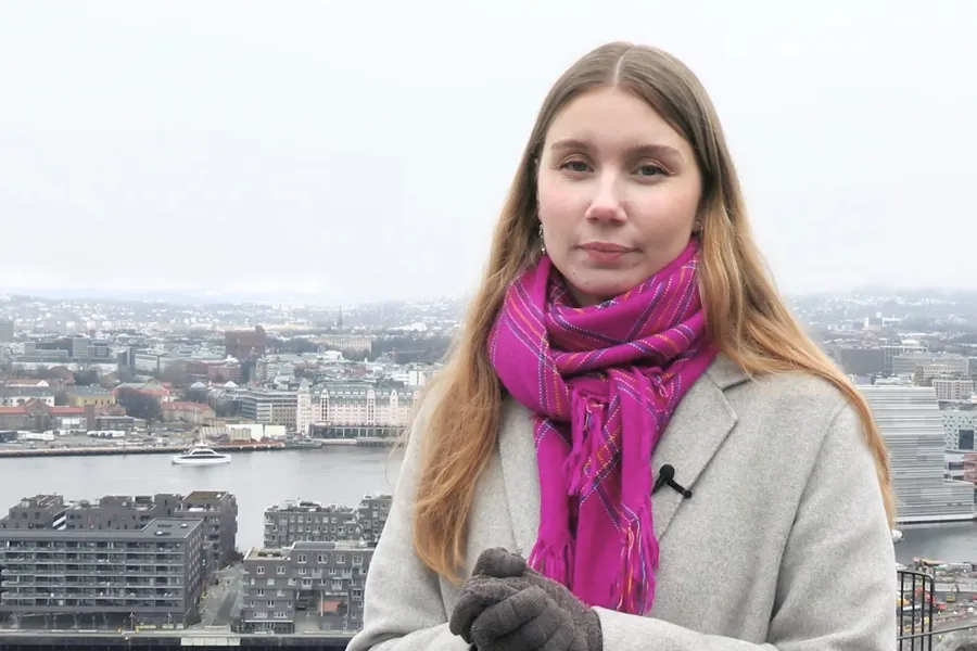 En kvinne med skjerf på hodet står på et tak med utsikt over en by