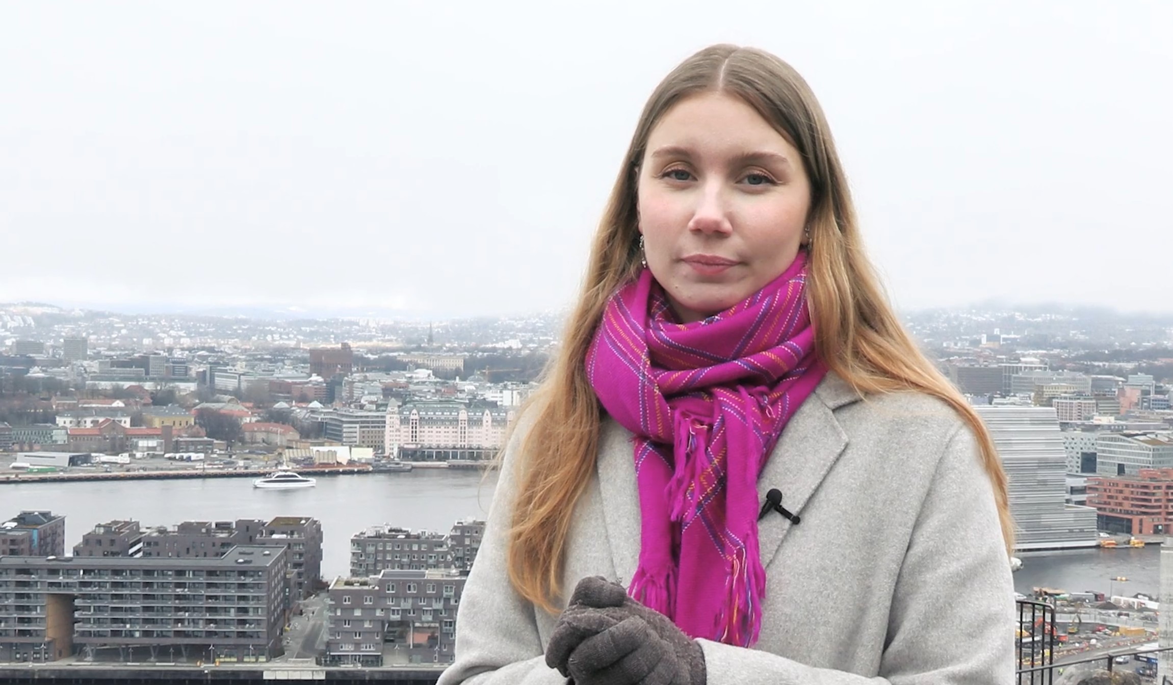 En kvinne med skjerf på hodet står på et tak med utsikt over en by