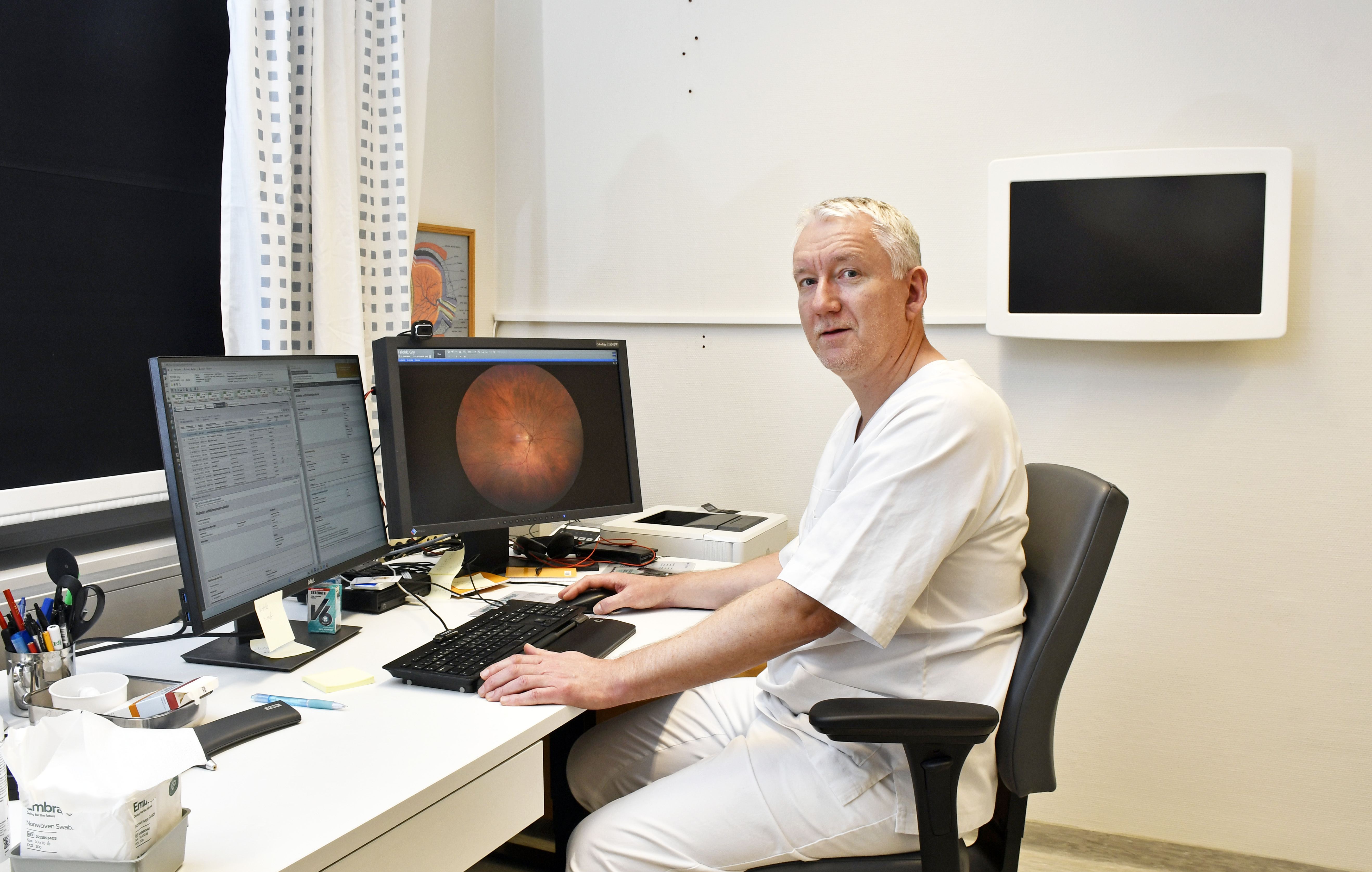 En mann som sitter ved et skrivebord med en datamaskin