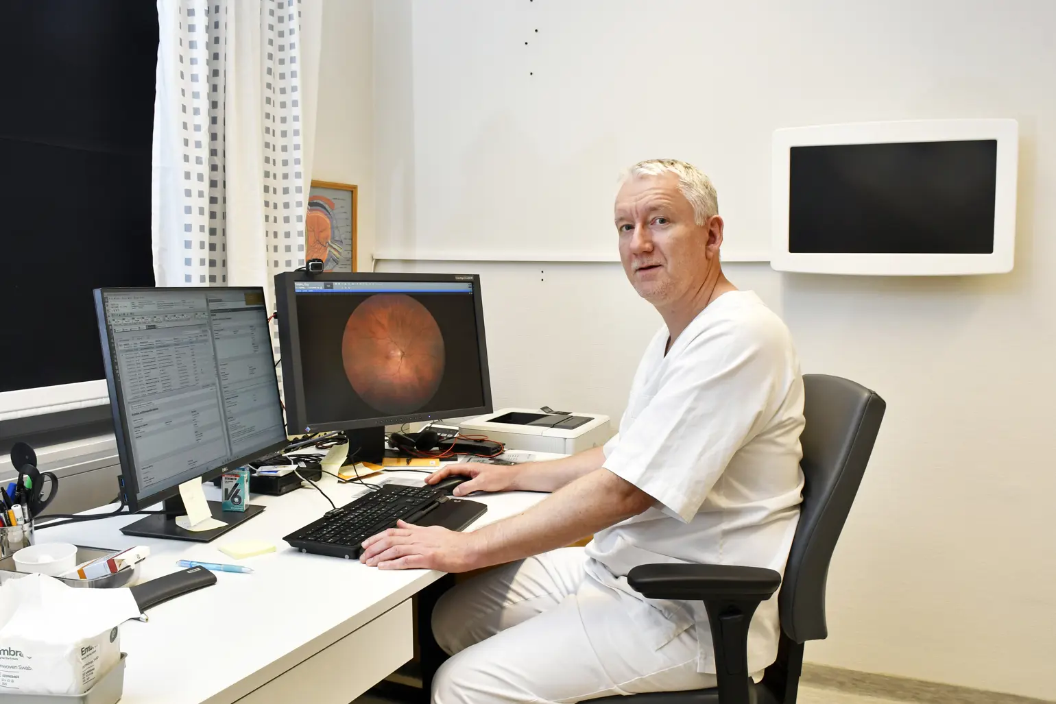 En mann som sitter ved et skrivebord med en datamaskin