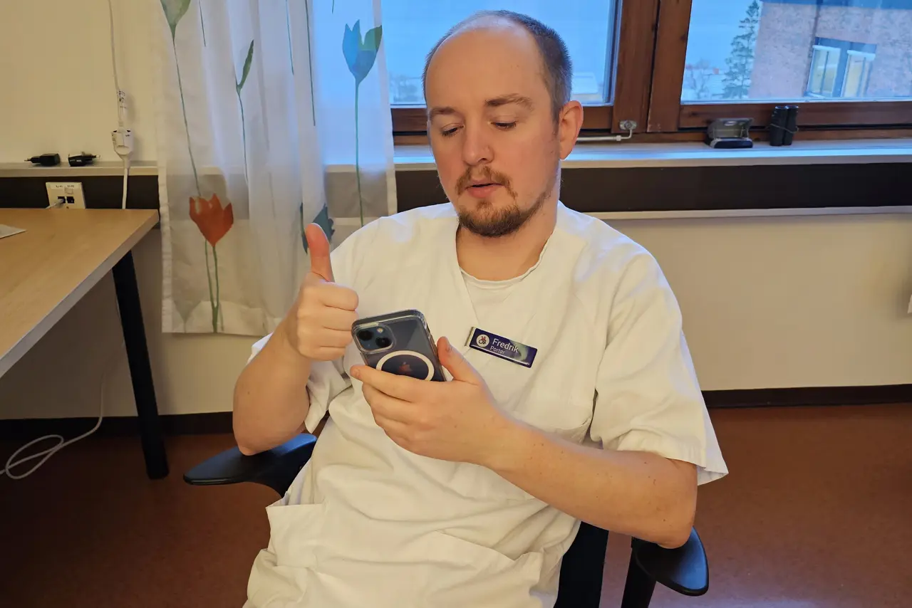 En person som sitter i en stol som holder en pistol og peker på kameraet